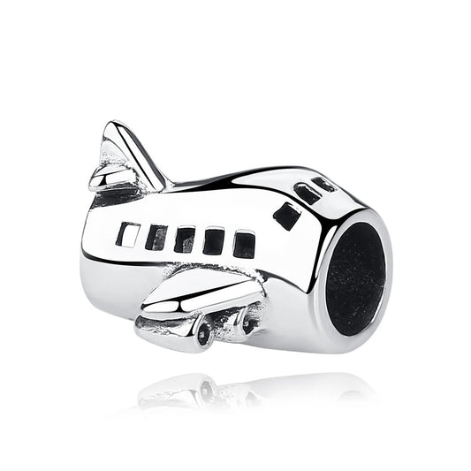 A polished silver airplane charm shaped like a passenger jet with detailed wings, tail fin, engine, and porthole windows, featuring a large central hole for attaching to a charm bracelet.