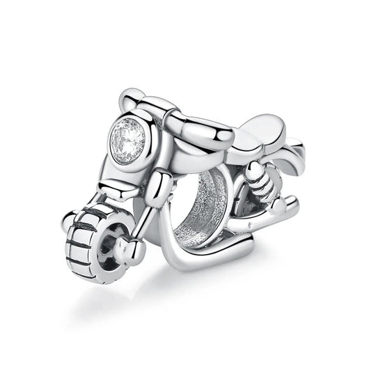 A silver-toned motorcycle scooter charm with detailed tyre tread, handlebars, a polished seat, and a round clear crystal set into the front headlight, photographed on a white background.