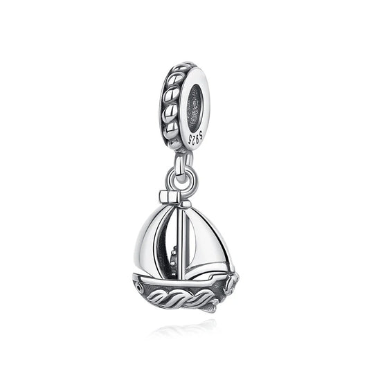 A 925 sterling silver dangle charm in the shape of a sailboat with raised sails, wave-textured hull, and an antiqued oxidized finish, attached to a rope-patterned bead clip