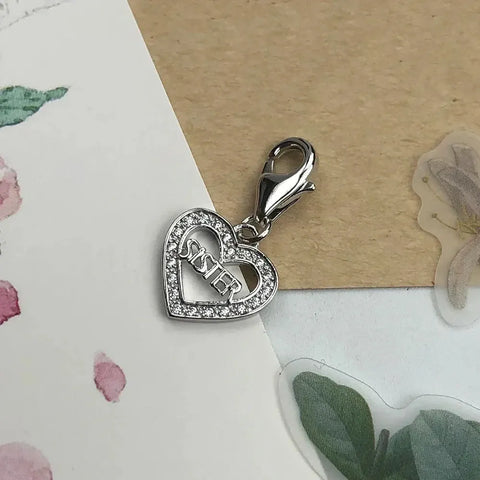 Silver heart charm with 'Sister' inscription.