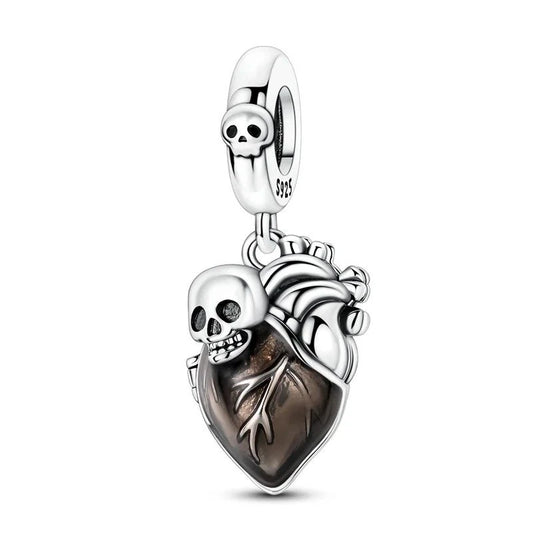 A sterling silver dangle charm shaped like an anatomical heart with dark smoky brown enamel, decorated with a silver skull and oxidized vessel details, with a clip bail at the top