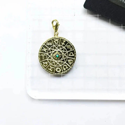 Gold zodiac charm with turquoise center.