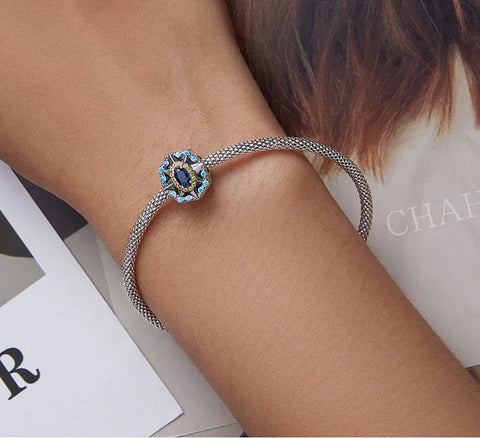 sterling silver charm with blue oval gemstone and yellow crystal accents