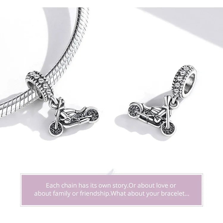 Two sterling silver Harley-Davidson motorcycle charms, one attached to a bracelet and the other resting on a flat surface, highlighting their intricate design.