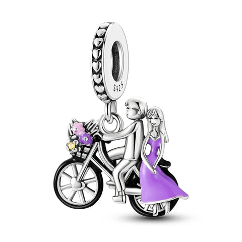 Sterling silver charm with a couple on a bicycle, featuring an enamel-painted purple dress, perfect for celebrating love and adventure.