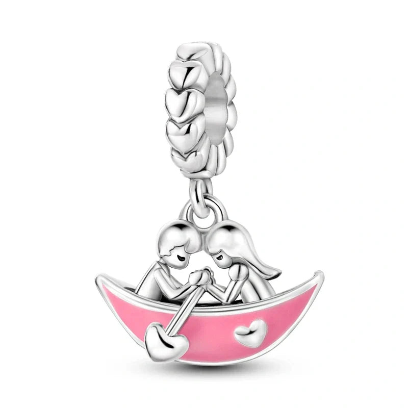 Sterling silver charm featuring a couple in a pink boat with heart accents, perfect for romantic occasions and love-themed collections.