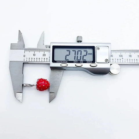 Red strawberry charm being measured.
