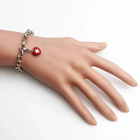 Silver chain bracelet with red heart charm.