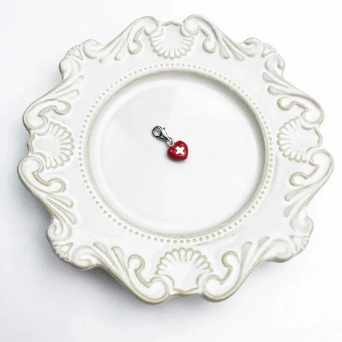 Red heart charm with white cross.