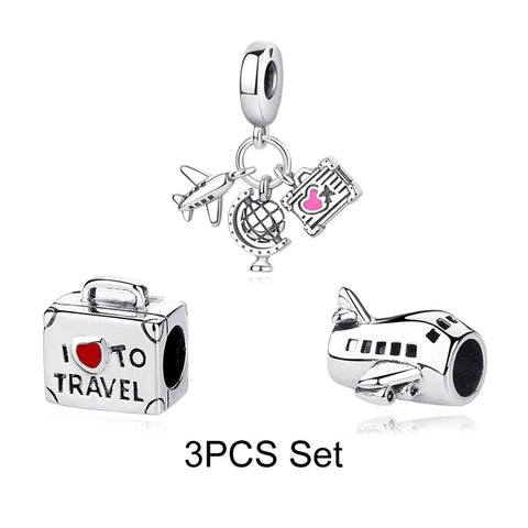 Travel Lover 3-Piece Charm Set – Plane, Globe & Suitcase - A silver-tone 3-piece travel charm set showing a suitcase bead reading I Love to Travel, an airplane bead, and a dangle charm with miniature plane, globe, and boarding pass with red and pink enamel