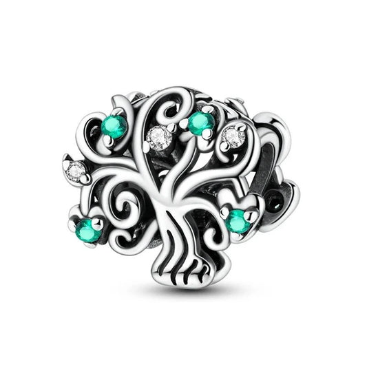 A silver oxidised openwork tree of life charm decorated with round emerald-green and clear crystal stones set among swirling branches