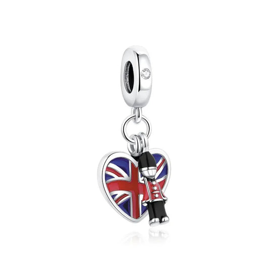 A silver clip-on charm featuring a heart-shaped Union Jack enamel pendant and a miniature Royal Guard figure dangle charm on a white background