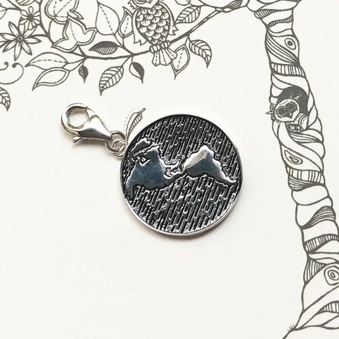 Silver charm with mountain design.