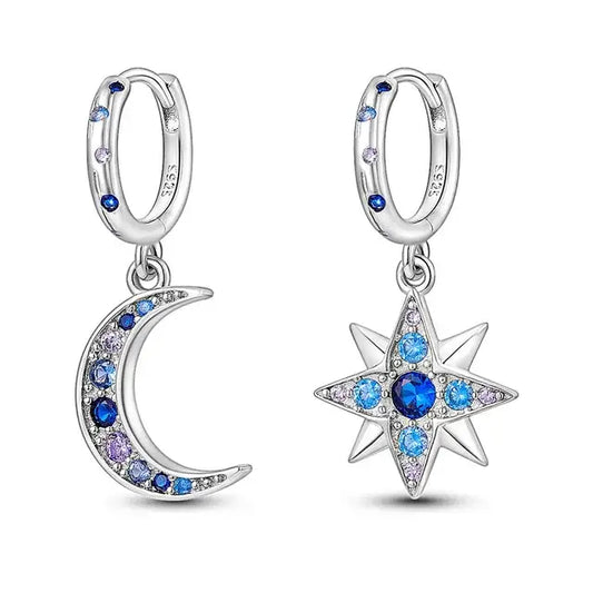Silver moon and star dangle earrings with blue crystals on a white background.