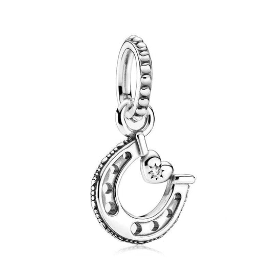 Silver lucky horseshoe charm with a heart and cubic zirconia, perfect for adding a touch of luck.